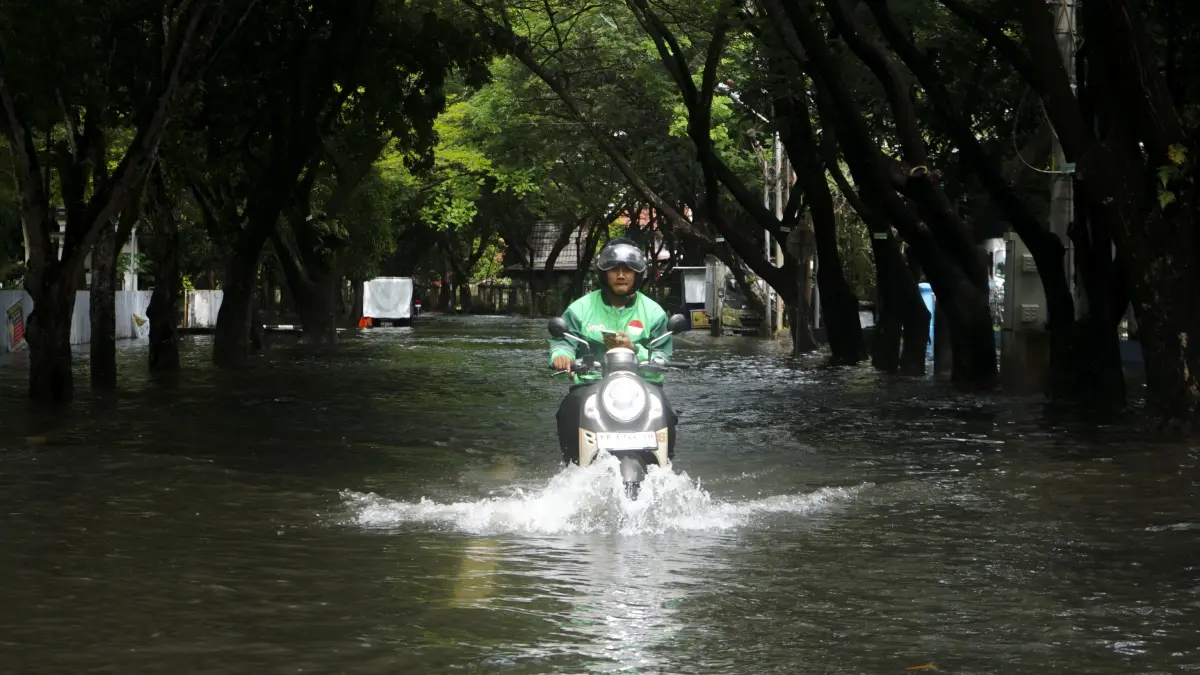 TERJANG BANJIR: Seorang pengemudi ojek online menerobos genangan banjir di Jalan D.A. Hadi, Pontianak, Selasa (16/6). Air pasang plus curah hujan tinggi dan Panjang yang terjadi sejak Senin mengakibatkan sejumlah ruas jalan dan kawasan permukiman terendam. (HARYADI/PONTIANAK POST)