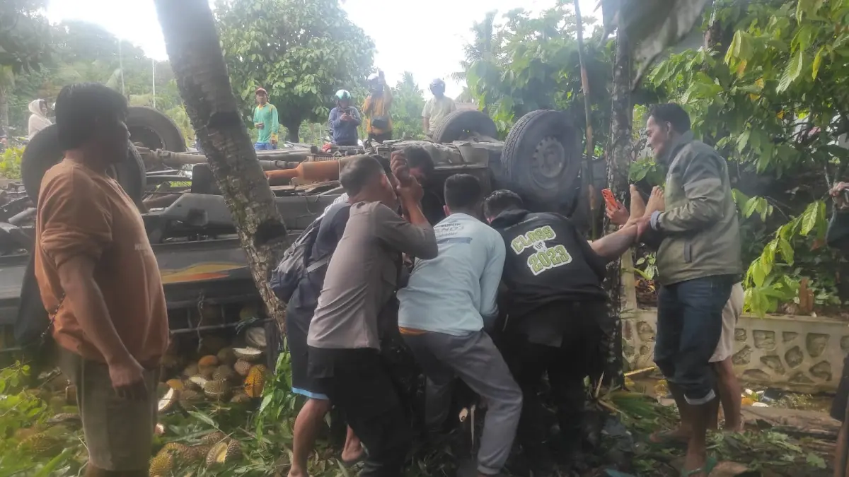 Korban pengendara pikap terbalik dievakuasi aparat kepolisian dan warga.