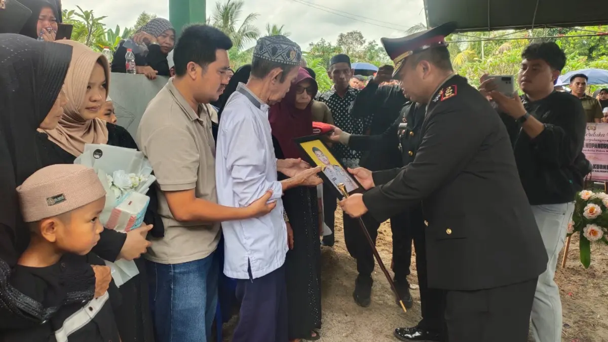 Kapolres Katingan AKBP Dodik Hartono menyerahkan foto Briptu (Anumerta) Nopandri Ramadhana kepada perwakilan keluarga usai prosesi pemakaman di Kabupaten Katingan, Minggu (5/7/2026). Briptu Nopandri gugur saat bertugas dan meninggalkan rencana meminang sang kekasih yang belum sempat terwujud. (JERI/KALTENG POS)