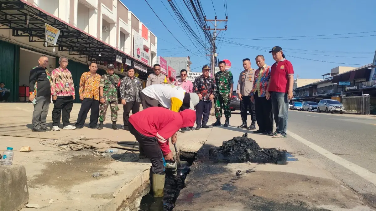 Warga membersihkan saluran di jalan jurusan Mempawah yang tertutup sampah. (ISTIMEWA)
