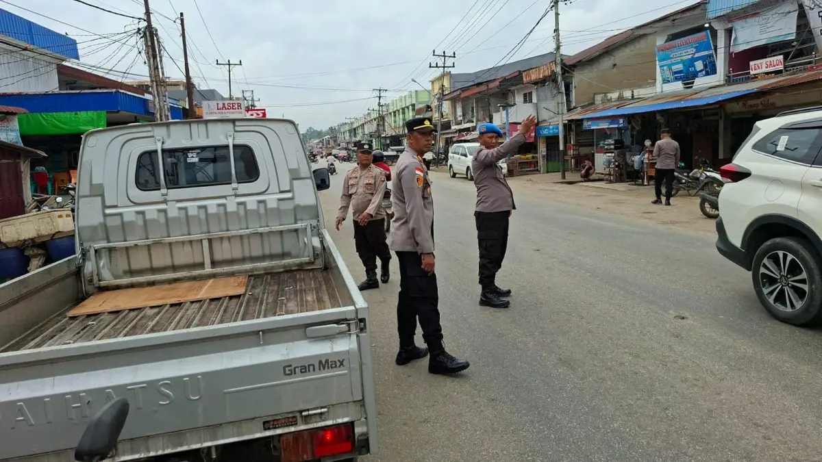 Personel Polsek Parindu menertibkan kendaraan yang parkir di bahu jalan kawasan Pasar Tumpah Pasar Bodok, Desa Pusat Damai, Sanggau, untuk mencegah kemacetan dan menjaga keselamatan lalu lintas.