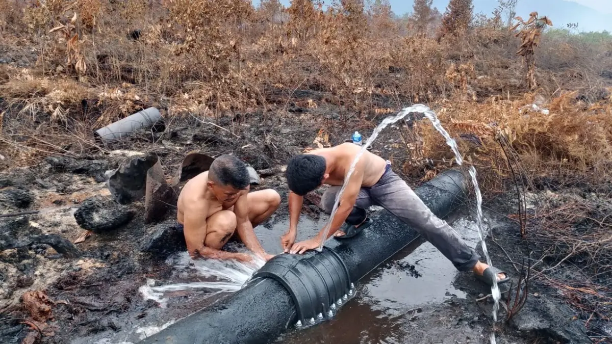 Petugas Air dari UPT Air Bersih Dinas PUPR KKU memperbaiki pipa induk yang bocor akibat bencana karhutla. (ISTIMEWA)
