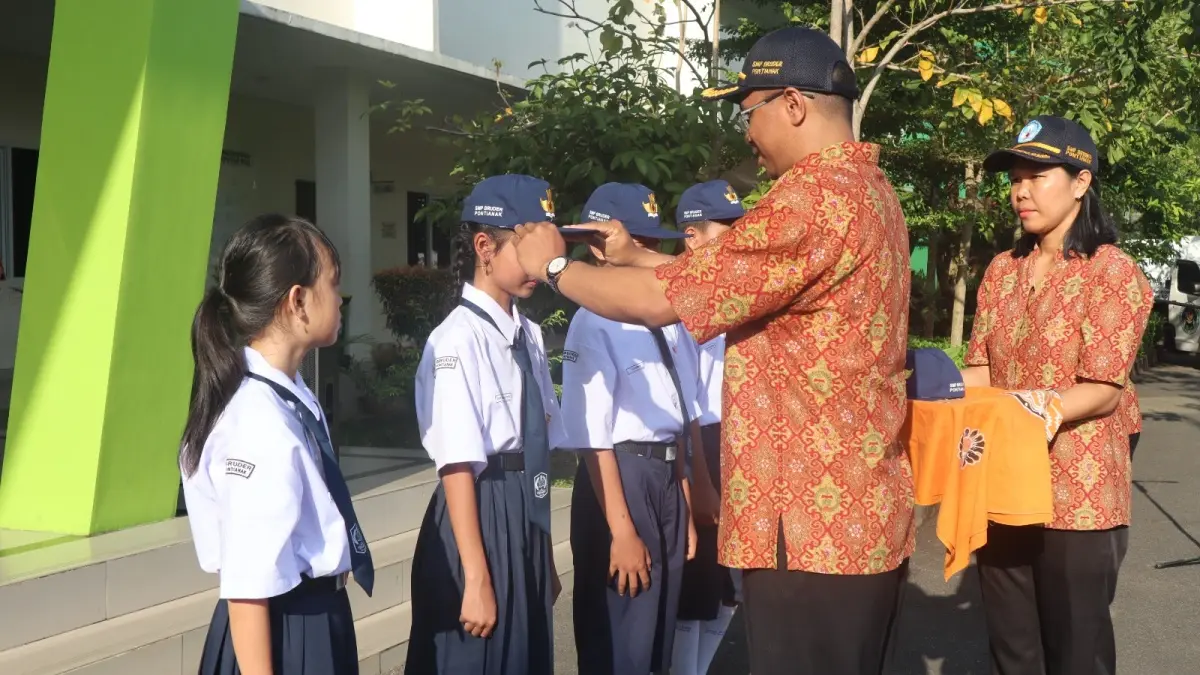 SMP Bruder Pontianak, Br. Ferdianus Jelahu MTB memakaikan topi sekolah secara simbolis kepada siswi baru SMP Bruder Pontianak. (ISTIMEWA)