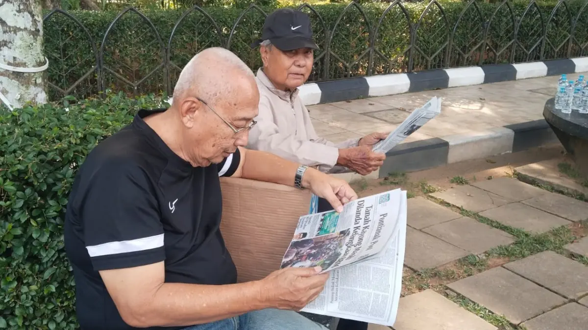 Agus (71) bersama rekannya sedang membaca koran Pontianak Post sambil menikmati suasana pagi di Taman Alun - Alun Kapuas tepatnya di kawasan depan Kantor Wali Kota Pontianak, Jumat (24/7). (WANDI/PONTIANAK POST)