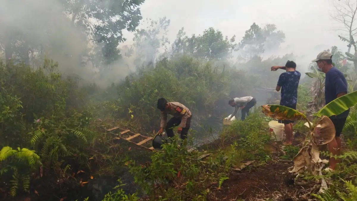 BERJIBAKU PADAMKAN KARHUTLA: Personel Polres Kubu Raya bersama pemadam kebakaran dan warga berjibaku mengangkut air menggunakan ember untuk memadamkan kebakaran hutan dan lahan (karhutla) yang mengancam permukiman di Komplek Fajar Asri 6, Kecamatan Sungai Raya, Kabupaten Kubu Raya, Minggu (26/7/2026). Keterbatasan sumber air memaksa petugas memanfaatkan cara manual agar kobaran api tidak merembet ke rumah-rumah warga. /IST