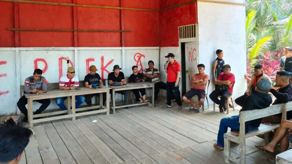 Kapolsek Meliau Iptu Supar memimpin mediasi bersama masyarakat, tokoh desa, dan unsur terkait di Tribun Pentas Seni Desa Pampang Dua, Kecamatan Meliau, Minggu (26/7). (ISTIMEWA)