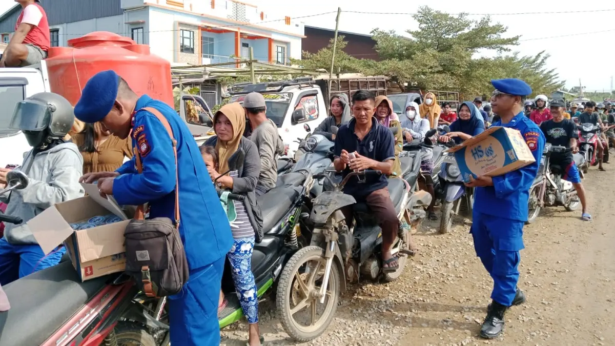 Personel Polairud Polda kalbar membagikan air minum kepada warga yang mengantre BBM di SPBU Melano Kayong Utara pada Senin (27/7). (ISTIMEWA