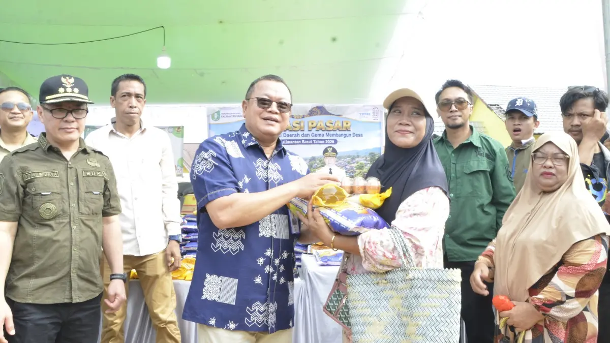 Direktur Utama Bank Kalbar, Rokidi saat menyerahkan bahan pokok kepada seorang peserta kegiatan Gerakan Pangan Murah (GPM) di halaman Pasar Daerah Sukadana. (DOK BANK KALBAR)
