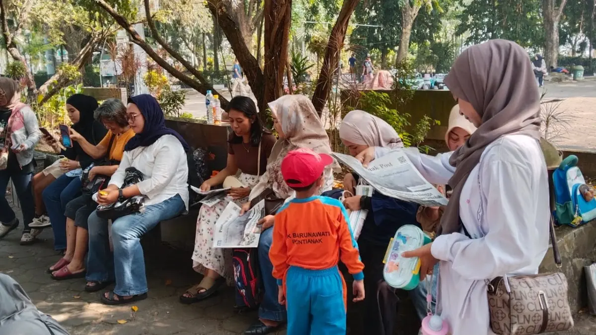 Tim Pontianak Post membagikan koran kepada orang tua dan anak didik TK Barunawati yang sedang mengikuti kegiatan belajar di luar kelas (outing class) di Taman Alun-Alun Kapuas, Jumat (7/8). (WANDI/PONTIANAK POST)