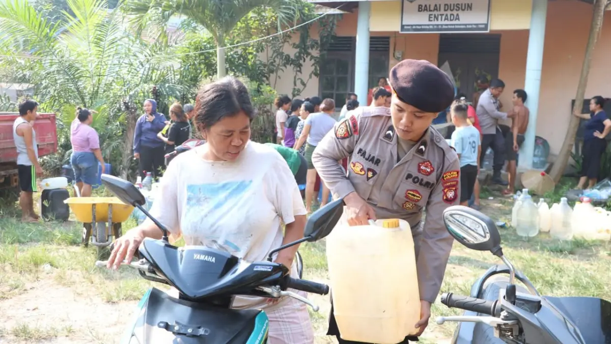 Anggota Polres Sekadau membantu menaikkan jeriken berisi air bersih ke sepeda motor warga saat penyaluran bantuan air di Dusun Entada, Sekadau.
