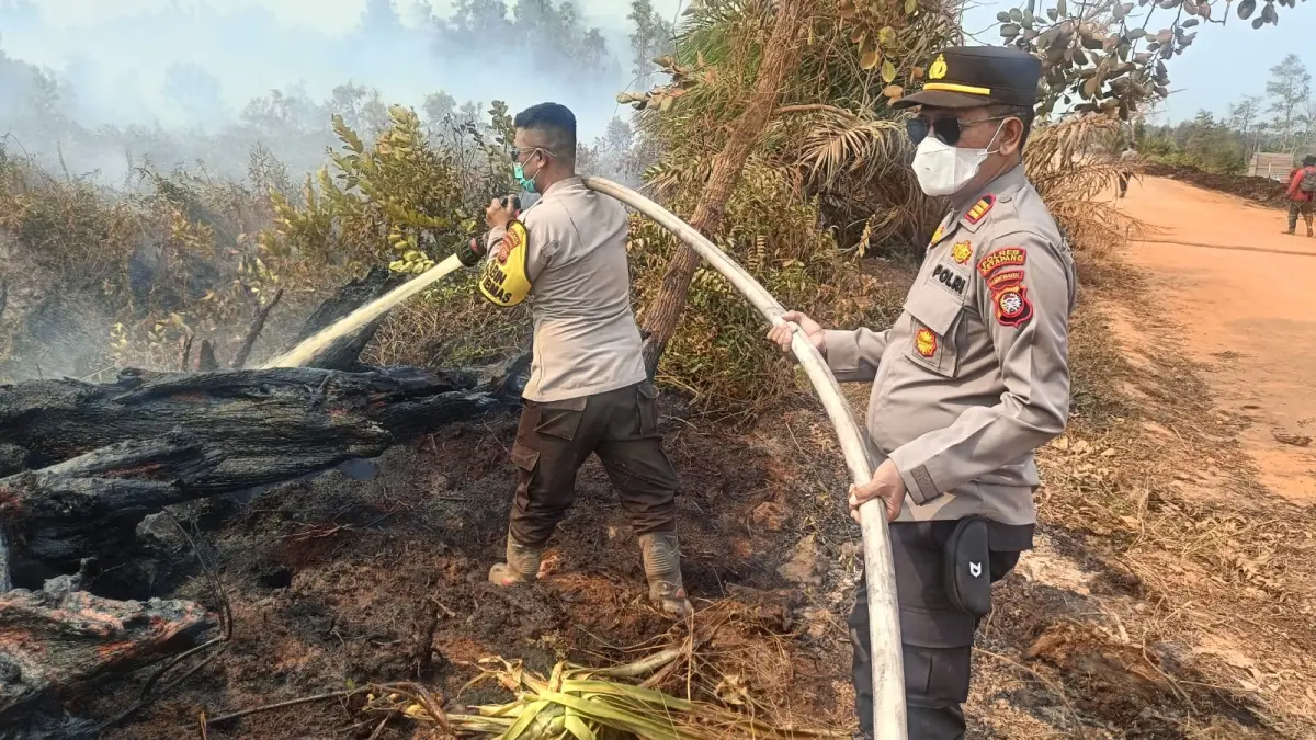 Personel kepolisian melakukan pembasahan untuk mendinginkan lahan gambut yang terbakar di kawasan Mensubuk, Desa Mayak, Kecamatan Muara Pawan, Kabupaten Ketapang, Selasa (11/8/2026). Pembasahan dilakukan untuk memastikan bara di dalam gambut tidak kembali memicu kebakaran.