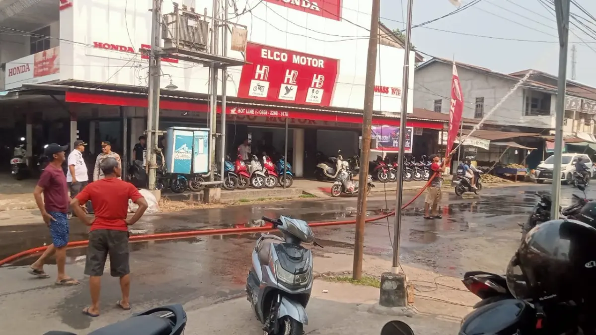 REDAM PANAS: Petugas menyemprotkan air ke jalan kawasan Pasar Sekadau untuk mengurangi debu dan panas di tengah cuaca kemarau, Rabu (12/8/2026).