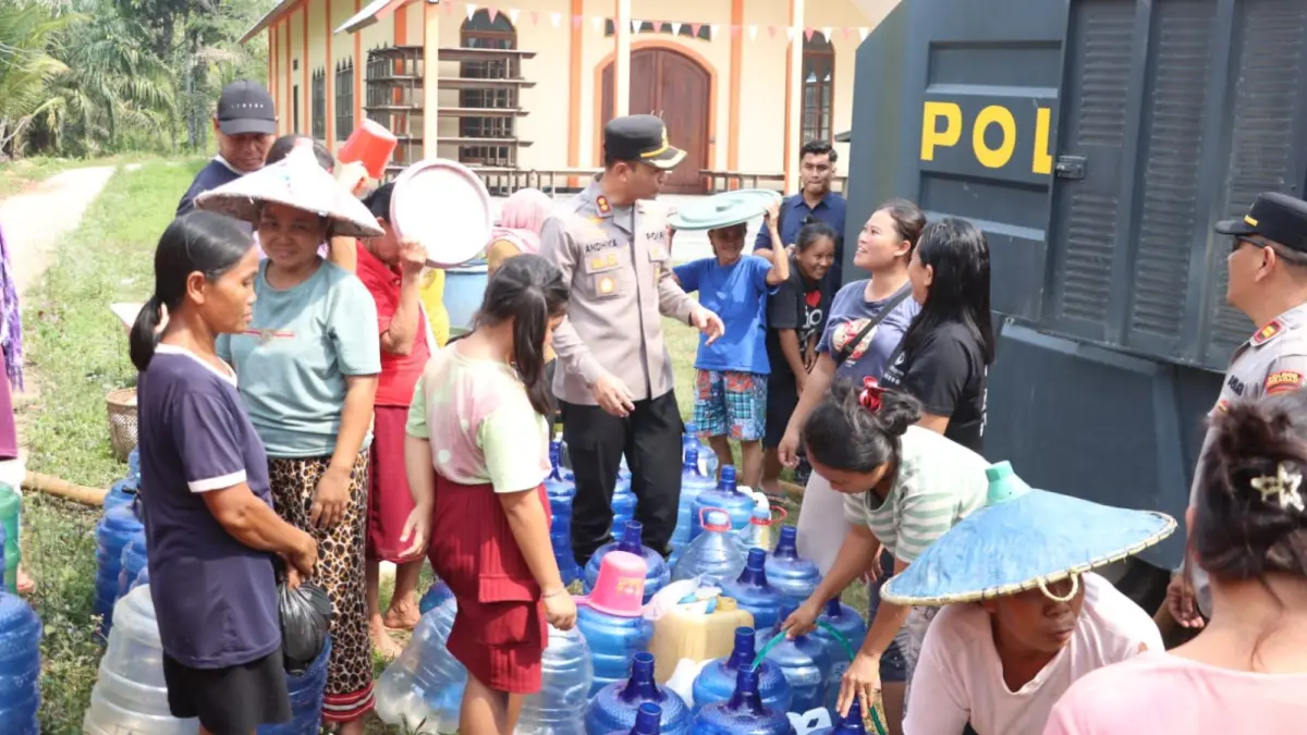 Kapolres Sekadau AKBP Andhika Wiratama ikut membantu warga mengisi air bersih saat distribusi 12.000 liter air di Desa Bokak Sebumbun, Kecamatan Sekadau Hilir, Kamis (13/8/2026).