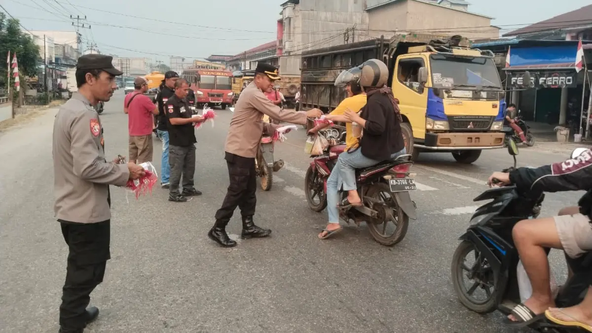 Personel Polsek Ngabang bersama Ormas Bala Dayak membagikan bendera merah putih kepada pengendara di Ngabang pada Rabu (11/8). (ISTIMEWA)&nbsp;