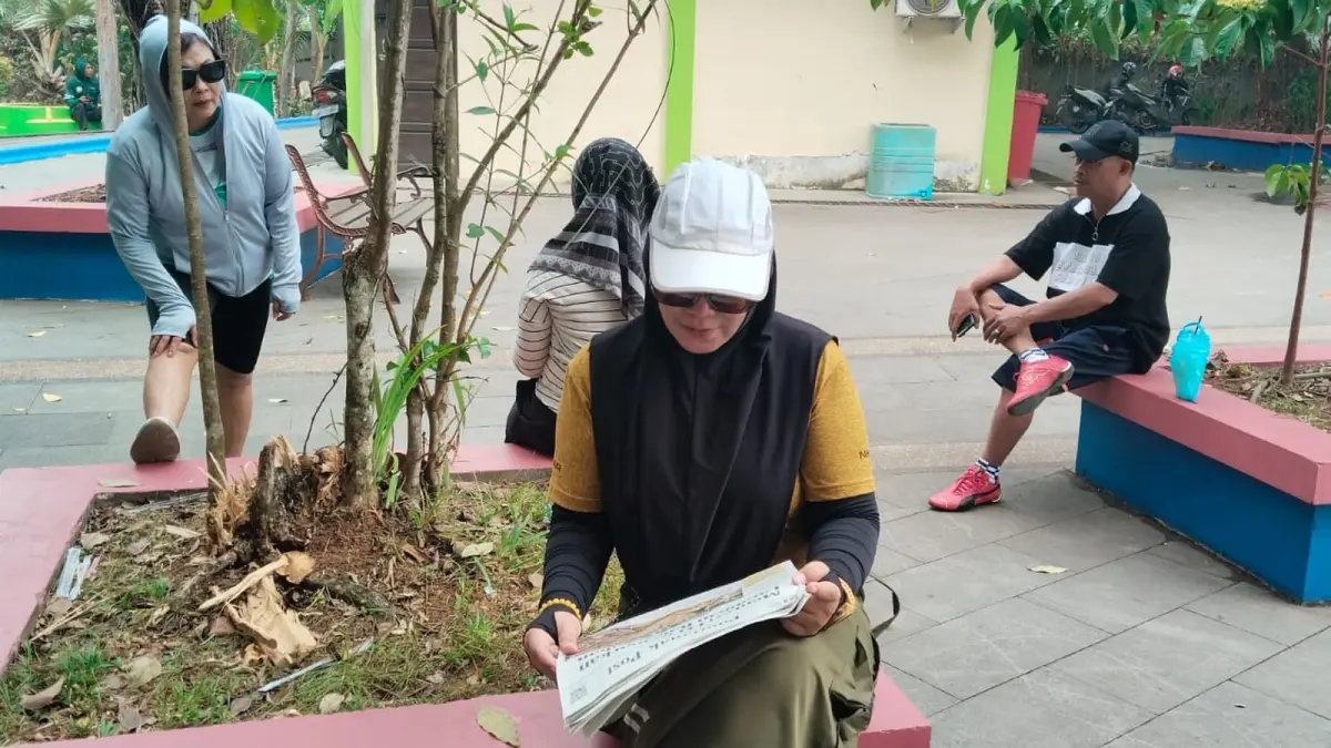 Nina Kartarineka (46) membaca koran Pontianak Post usai berolahraga di kawasan Tugu Digulis Universitas Tanjungpura (Untan), Pontianak, Jumat (14/8). (WANDI/PONTIANAK POST)