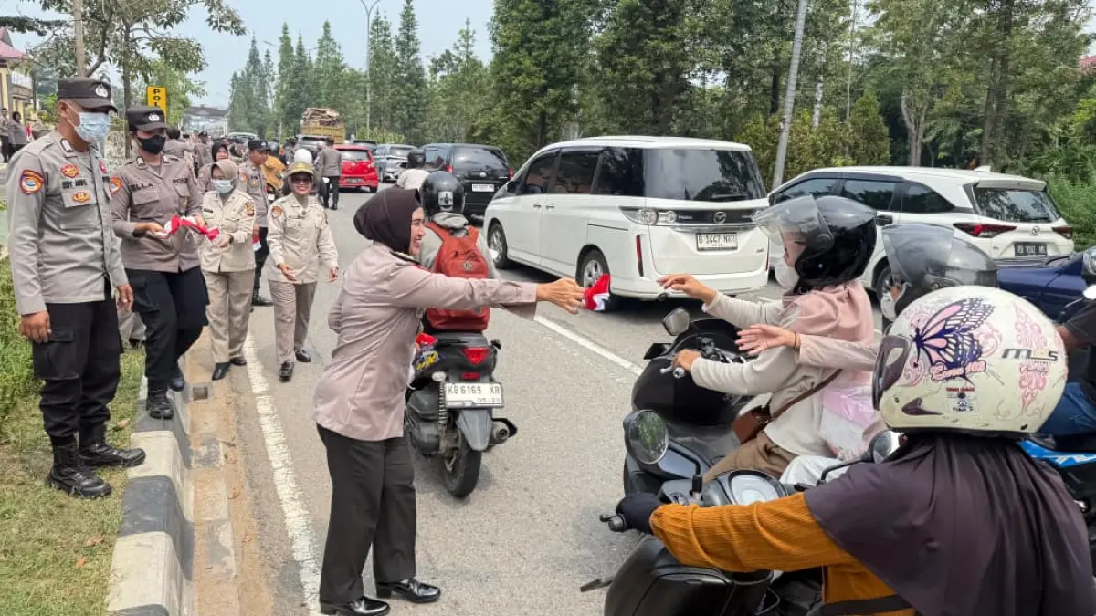 Personel Polda Kalbar membagikan bendera Merah Putih kepada pengguna jalan di depan Mapolda Kalbar, Jalan Ahmad Yani, Pontianak, dalam rangka menyemarakkan HUT ke-81 Kemerdekaan RI, Jumat (14/8/2026).