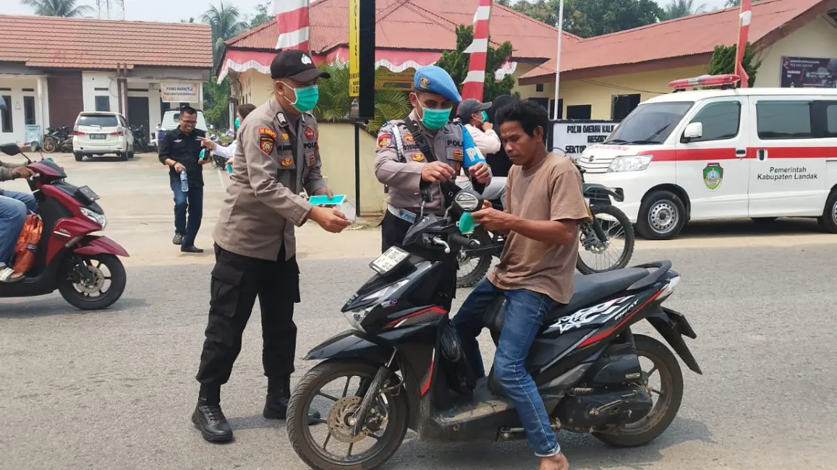 CEGAH DAMPAK KABUT ASAP: Petugas membagikan masker dan vitamin C kepada warga di Mempawah Hulu, Kabupaten Landak, untuk mengurangi risiko gangguan pernapasan.