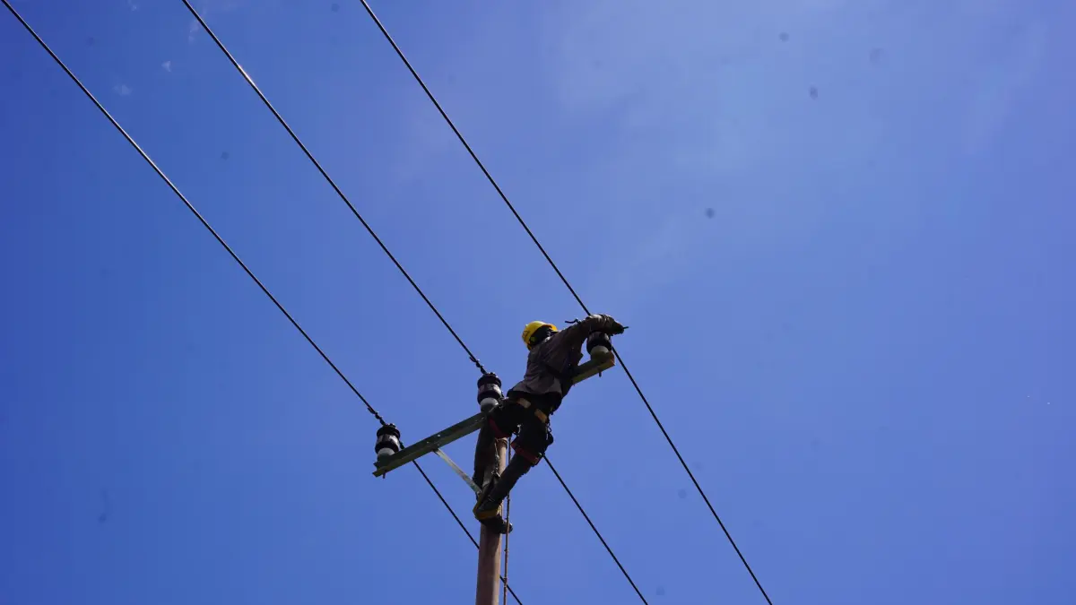 Petugas Pembangunan Lisdes melakukan pengikatan kabel 20 kV di isolator jaringan distribusi, salah satu tahapan penting dalam pembangunan listrik desa di Muara Baru, guna memastikan jaringan siap mengalirkan listrik secara andal bagi masyarakat.