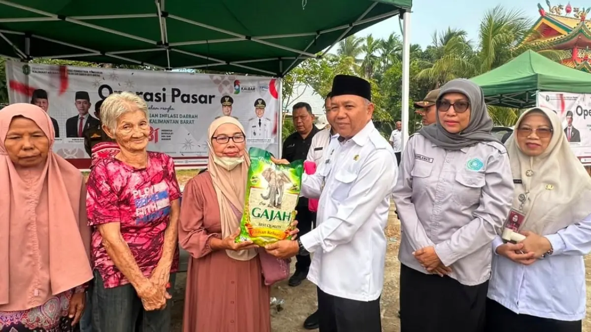 Wabup Mempawah, Juli Suryadi Burdadi, menyerahkan paket sembako murah kepada salah seorang warga.
