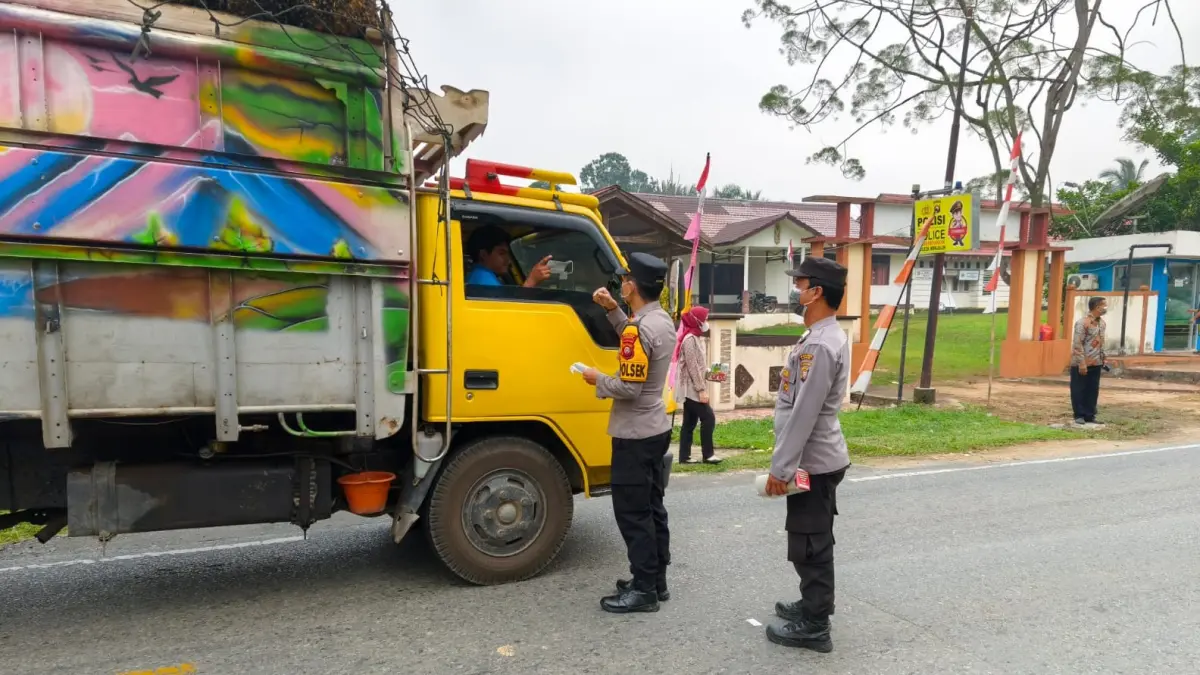 Personel Polsek Menjalin membagikan masker kepada sopir truk yang melintas di depan Mako Polsek Menjalin, Kabupaten Landak, sebagai upaya mengurangi paparan kabut asap, Kamis (20/8/2026).