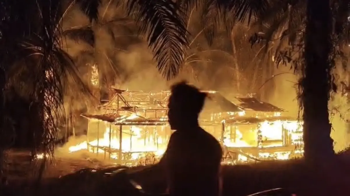 Seorang warga melintas di sebuah rumah yang dibakar orang tak dikenal di Air Upas, Rabu (19/8) malam.