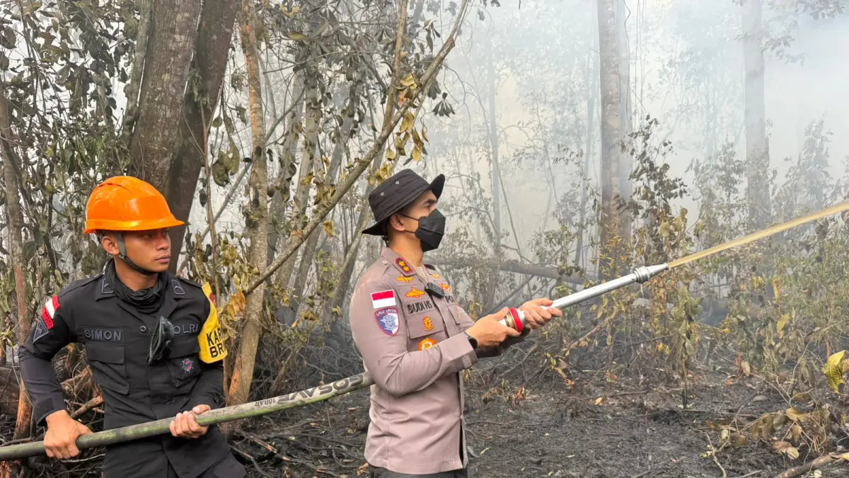 PADAMKAN KARHUTLA: Kapolres Sintang AKBP Budi Hartono Sutrisno turun langsung menyiramkan air untuk memadamkan titik api di lahan gambut, Sintang, Sabtu (22/8). Upaya ini dilakukan bersama tim gabungan untuk mencegah api kembali meluas.
