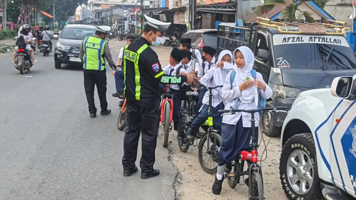 Personel Satlantas Polres Bengkayang membagikan masker kepada pelajar untuk mengurangi paparan kabut asap saat beraktivitas di luar rumah, Senin (24/8/2026).