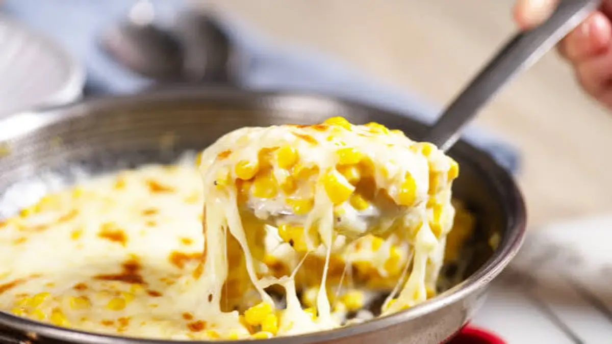 Korean Corn Cheese disajikan hangat dalam wajan dengan lapisan mozzarella yang meleleh dan taburan daun bawang.