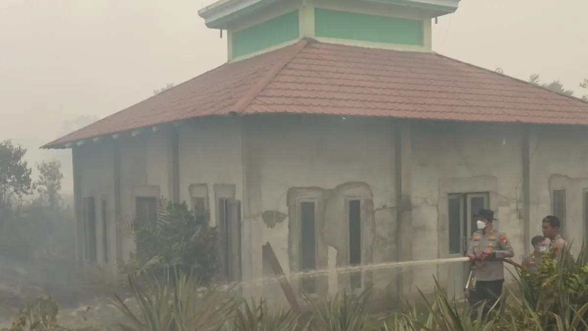 SELAMATKAN MASJID: Tim gabungan memadamkan karhutla yang nyaris mencapai Masjid Baiturrahman di Dusun Tanjung Puri, Arang Limbung, Kubu Raya, Jumat (28/8/2026). Api hanya berjarak sekitar sejengkal dari dinding masjid. (POLRES KUBU RAYA)