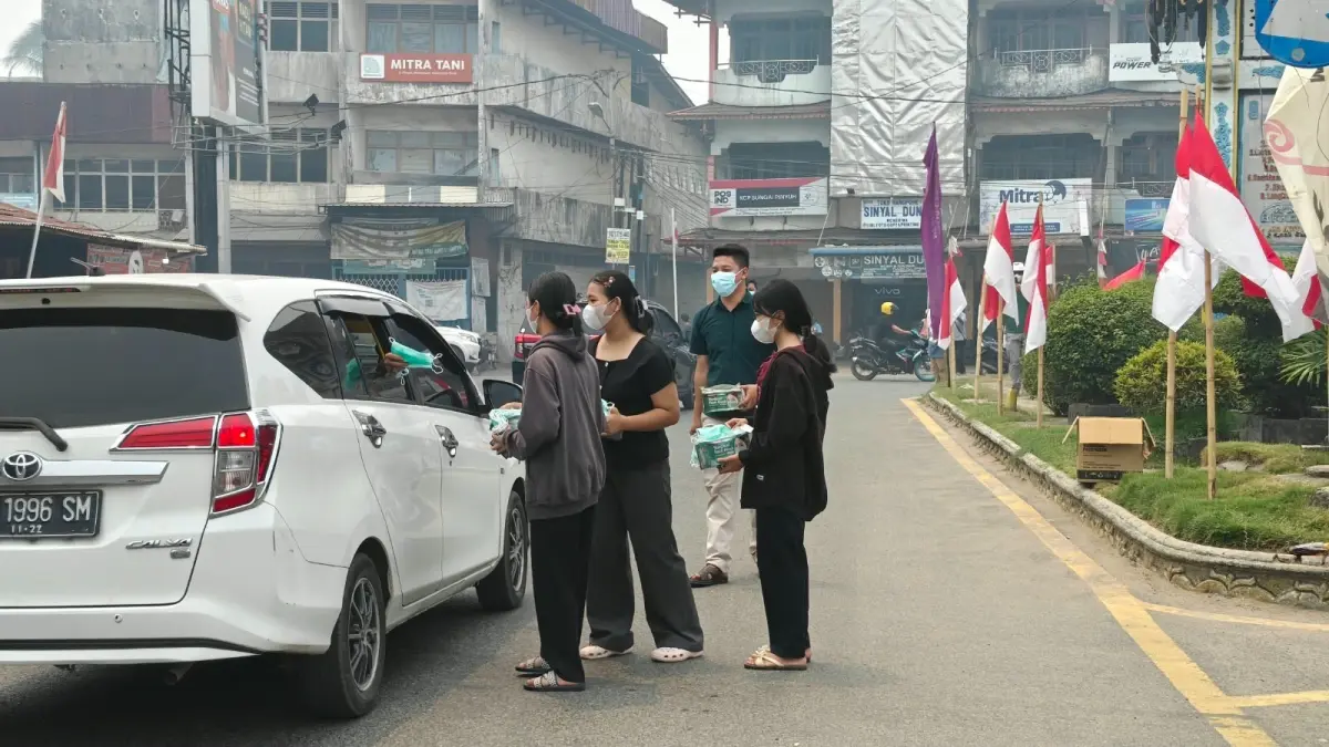 Paroki Santo Christophorus membagikan masker kepada pengendara yang lewat di tugu jam Sungai Pinyuh.