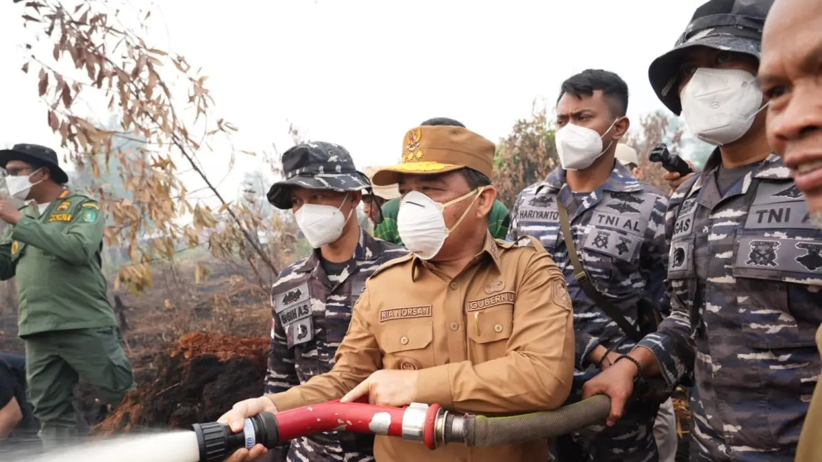 Gubernur Kalimantan Barat Ria Norsan saat menyemprotkan air untuk memadamkan api di lahan yang terbakar. (Adpim Pemprov Kalbar)