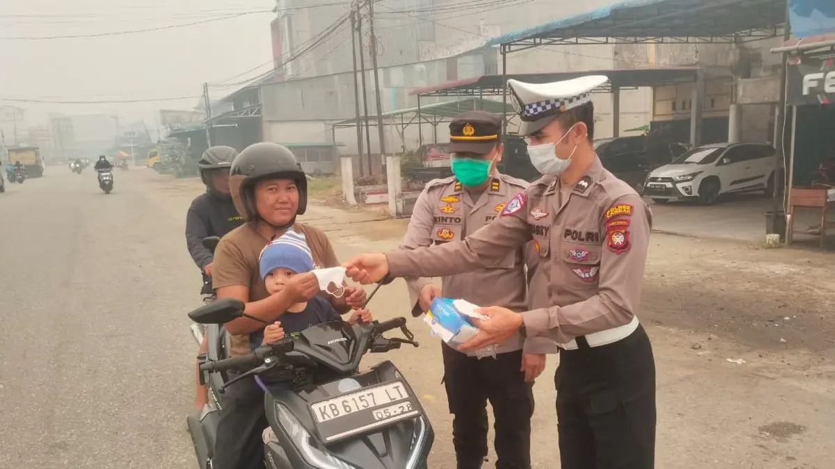 Personel polsek Ngabang membagikan masker kepada pengguna jalan di Kecamatan Ngabang pada Kamis (3/9). Langkah itu diambil sebagai antisipasi dampak buruk kabut asap yang kian pekat. (ISTIMEWA)