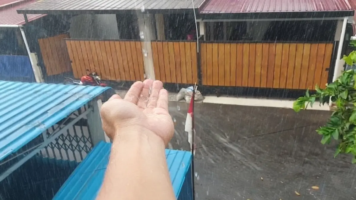 HUJAN DINANTI: Seorang warga menadahkan tangan saat hujan membasahi Kota Pontianak, Jumat (4/9) sore. Hujan singkat membawa kelegaan di tengah kabut asap, tetapi belum cukup mengakhiri ancaman karhutla.