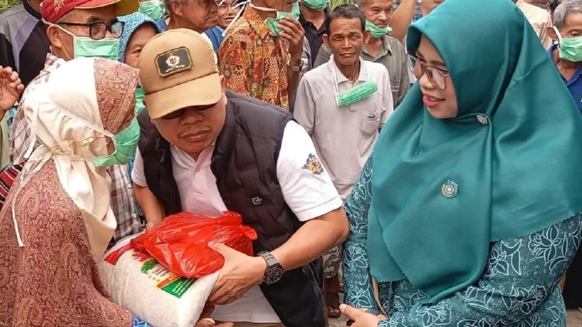 Bupati Sambas H Satono didampingi Ketua TP PKK Hj Yunisa  menyerahkan paket sembako di Desa Sendoyan Kecamatan Sejangkung.