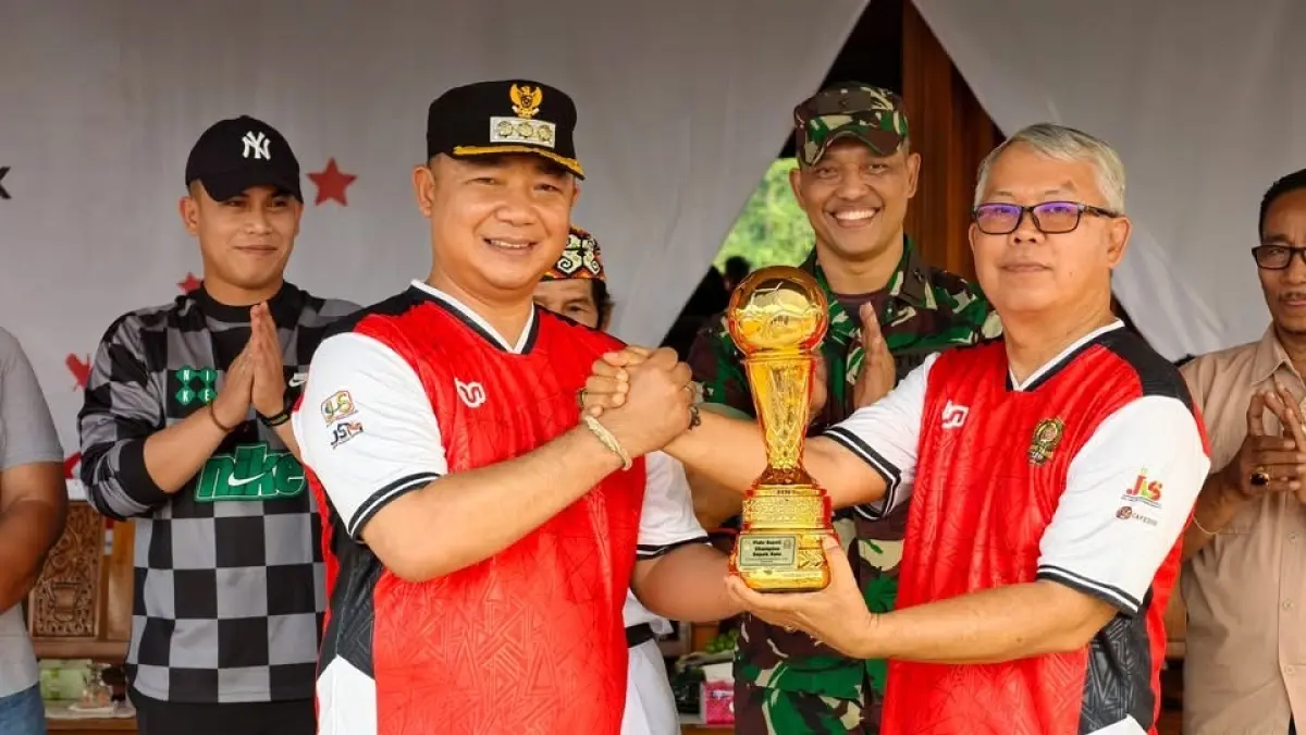 Bupati Ketapang, Alexander Wilyo, menyerahkan piala kepada panitia sebagai tanda dimulainya turnamen Karang Taruna Tunas Cempaka Cup Desa Muara Jekak 2026, Senin (14/9). (ISTIMEWA)