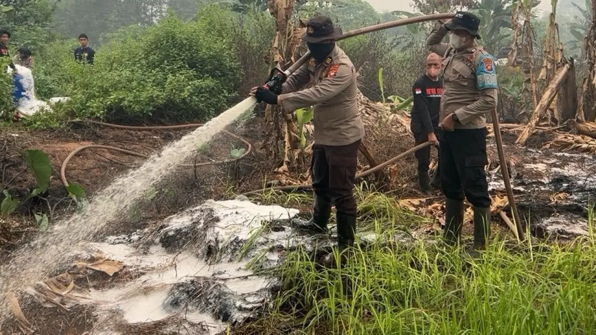 Petugas Polres Kubu Raya melakukan pemadaman dan pendinginan di lahan yang masih mengeluarkan asap di Desa Limbung. (Humas Polri)