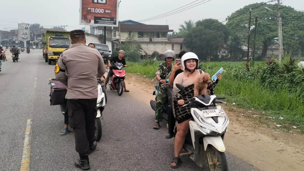 Kapolsek Kembayan Iptu Hudson Siahaan bersama personel Polsek Kembayan membagikan masker kepada warga dan pengendara di Jalan Raya Lintas Malindo, depan Mapolsek Kembayan, Selasa (22/9). (ISTIMEWA)