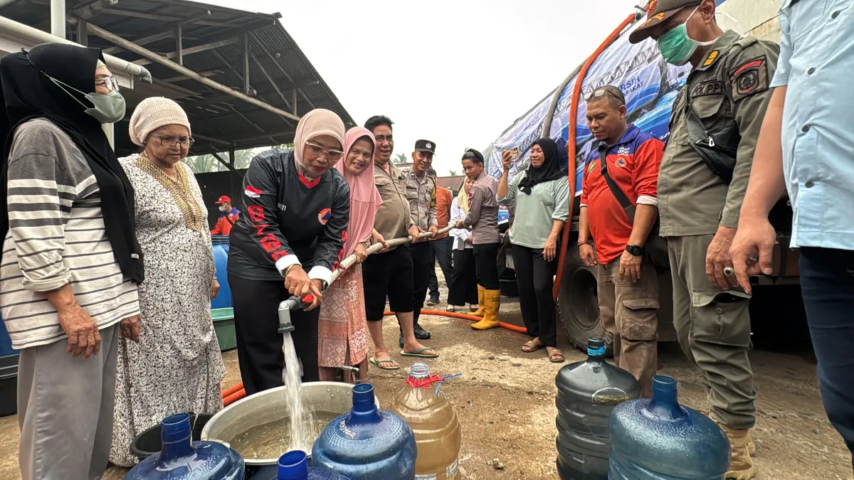Bupati Mempawah, ERLINA mengisi wadah dengan air bersih untuk warga Desa Wajok Hilir.