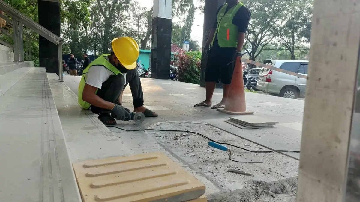 Pengerjaan guiding block atau jalur pemandu bagi teman disabilitas di kantor terpadu Sutoyo pada Selasa (29/9). (STIMEWA)