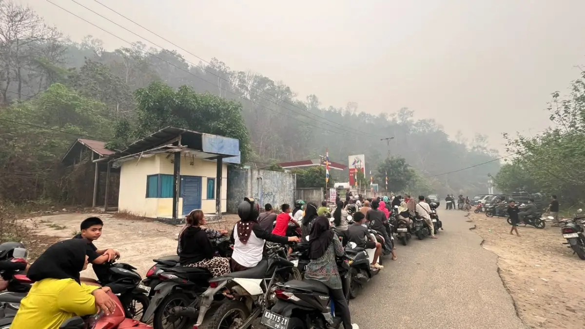 ANTREAN BBM: Warga mengantre untuk mendapatkan BBM di SPBN Sukadana, Kabupaten Kayong Utara, Kalimantan Barat, Rabu (14/10/2026). Antrean kendaraan mengular hingga ke jalan raya di tengah kabut asap yang masih mengganggu aktivitas masyarakat. DANANG PRASETYO/PONTIANAK POST)