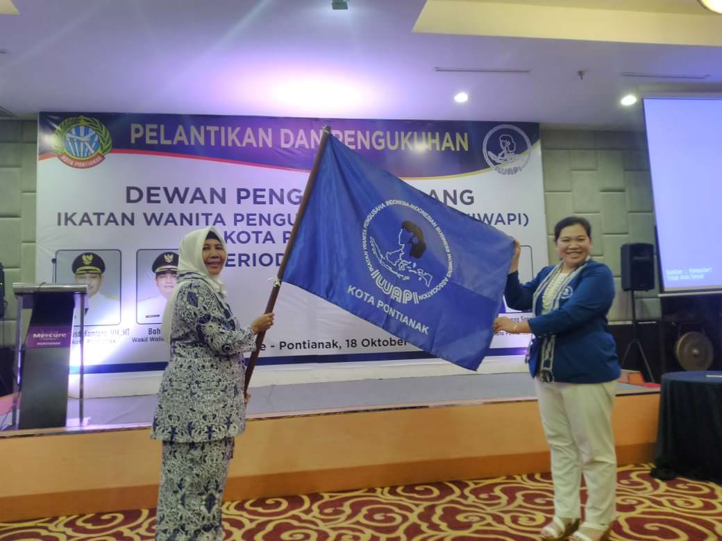 SERAHKAN : Ketua Umum DPD Iwapi Kalbar, Oktavia (kanan) menyerahkan pataka kepada Ketua Umum DPC Iwapi Kota Pontianak,  Imtihani, saat pelantikan dan pengukuhan Ketua DPC Iwapi Kota Pontianak, di Hotel Mercure Pontianak, Jumat (18/10)