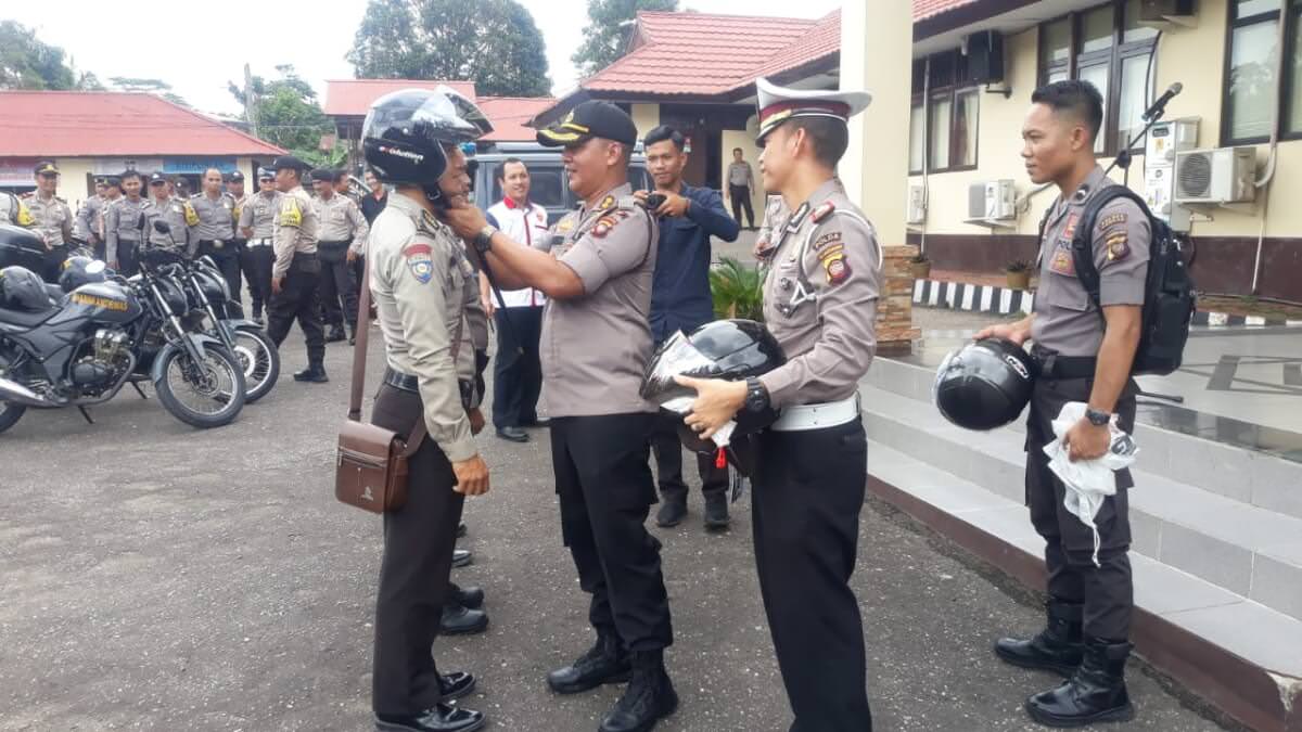 PENGHARGAAN: Kapolres Landak AKBP Ade Kuncoro saat memasangkan helm kepada Bripka Susanto Atung, Selasa (3/12). ISTIMEWA