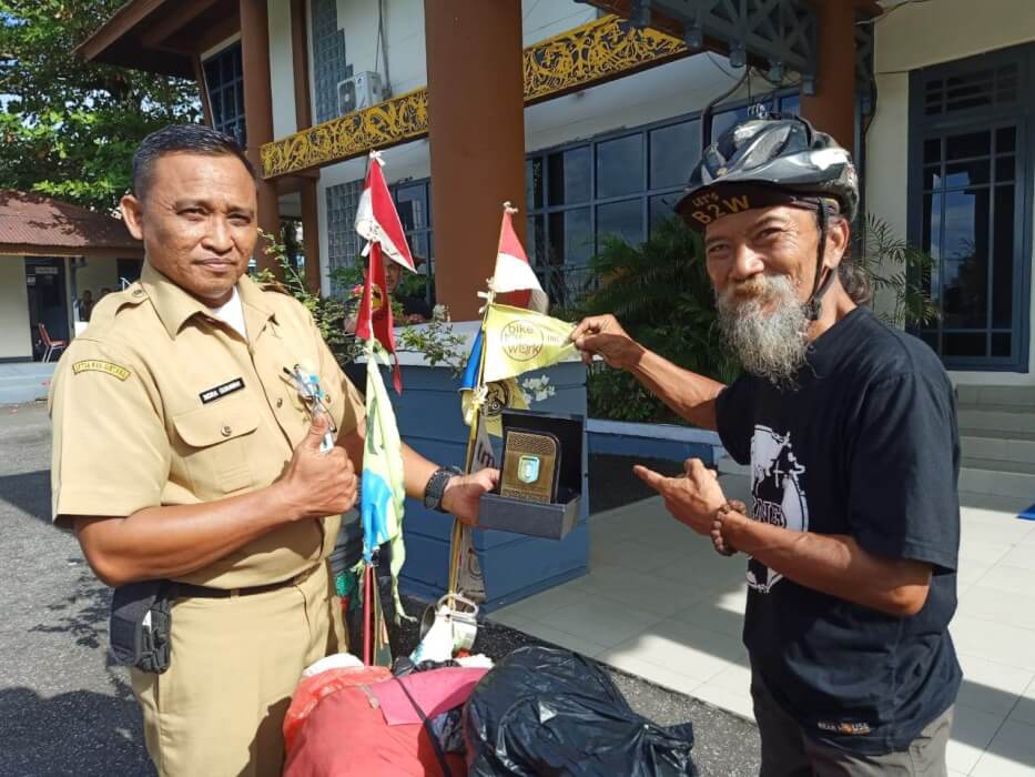 PLAKAT: John Maynard diberi plakat oleh Pemkab Sintang usai bersepeda dari Senaning, perbatasan di Kabupaten Sintang. FIRDAUS DARKATNI/PONTIANAKPOST