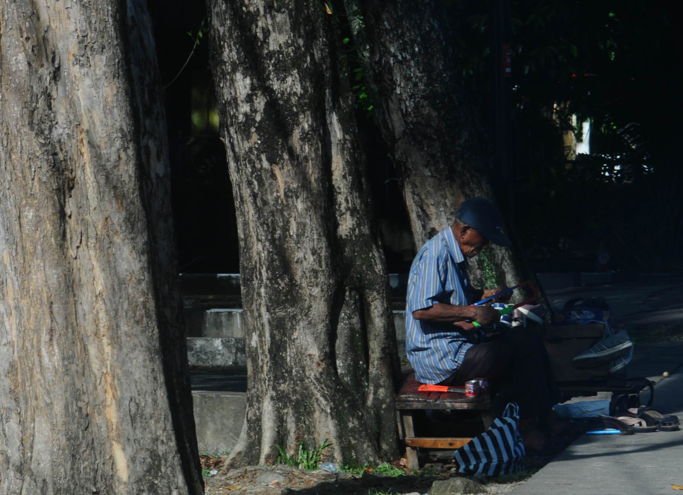 TETAP BEKERJA: Seorang lansia bekerja memperbaiki sepatu di pinggir ruas Jalan Alianyang, Sabtu (30/5). HARYADI/PONTIANAK POST