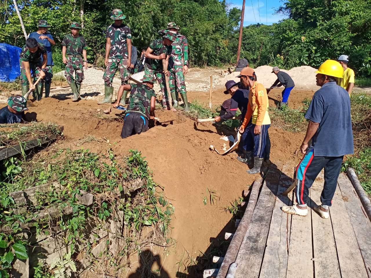 Anggota Satgas bersama warga bahu membahu membuat lubang pondasi jembatan dan penyiapan bahan-bahan di Desa Danti, Kecamatan Sanggau Ledo, Kabupaten Bengkayang.