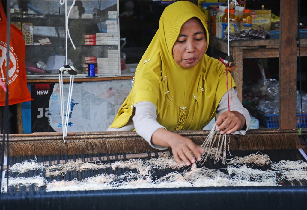 MENENUN: Perajin tenun Kurniati menyelesaikan pembuatan kain tenun di rumahnya di Jalan Khatulistiwa, Pontianak Utara. Usaha pembuatan kain tenun telah ditekuninya sejak lama.