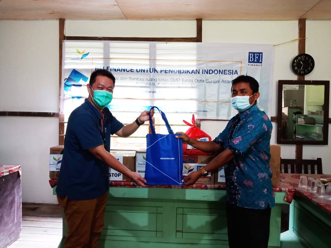 Area Manager BFI Finance Wilayah Pontianak Bambang Hartoyo Soenarso (kiri) menyerahkan bantuan secara simbolis kepada Kepala Sekolah SMP Tunas Duta Moral Pincawan S.Pd (kanan)