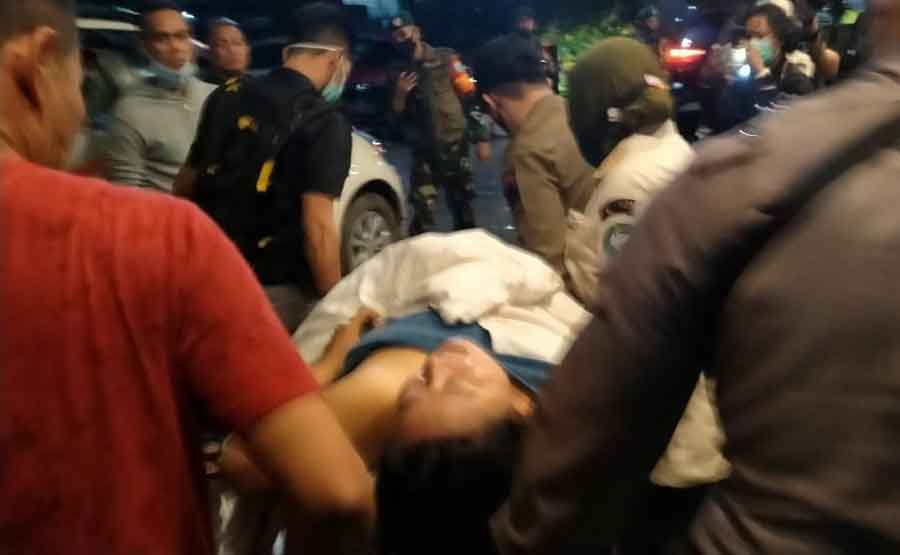 Petugas mengevakuasi seorang wanita yang melompat dari lantai empat hotel Borneo, saat razia berlangsung.