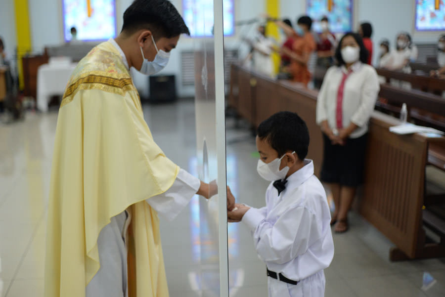 PERTAMA: Pastor Flavianus Santo Andreas CM memberikan komuni pertama kepada anak-anak di Gereja Keluarga Kudus, Pontianak. BUDI MIANK/PONTIANAKPOST