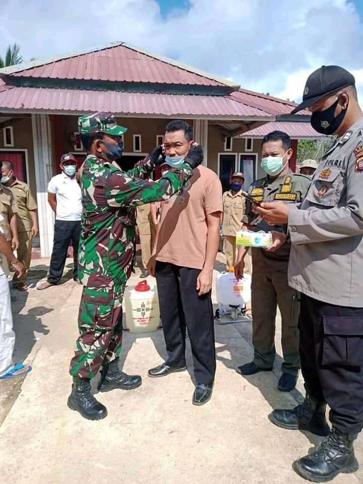 PASANGKAN MASKER: Sertu Lakip saat memasangkan masker pada salah satu warga Desa Nanga Tikan, Kecamatan Kayan Hilir, baru-baru ini.ISTIMEWA/PONTIANAK POST